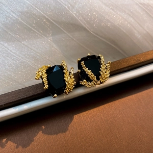 Détail de clous d'oreilles épi de blé plaqués or avec pierres noires facettées