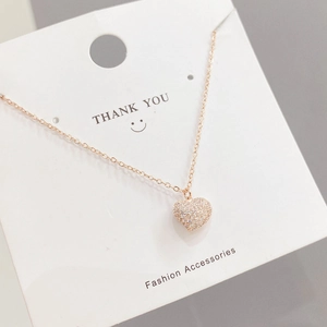 Close-up of rose gold heart necklace with sparkling pavé crystals on a display card