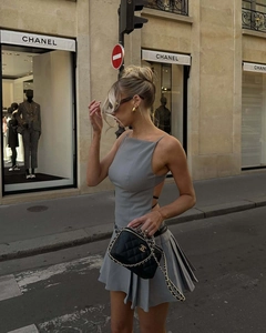 Détail d'une robe grise plissée dos nu à bretelles croisées et sac à chaîne métallique
