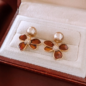 Macro detail of vintage gold-plated flower earrings with pearls and amber enamel