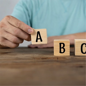 Close-up of hand holding a 1-inch wooden alphabet block with black letter A engraving