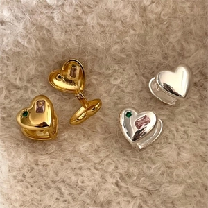 Detailed view of gold and silver heart hoop earrings with pink and green gemstones