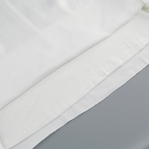 Détail des couches de tissu blanc et de la couture fine de l'ourlet roulé sur la robe