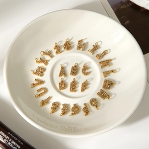 Détails de 26 pendentifs alphabet dorés sertis de strass brillants sur un plateau