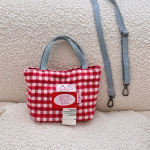 Detail of red plaid wool tote bag featuring denim handles and detachable shoulder strap