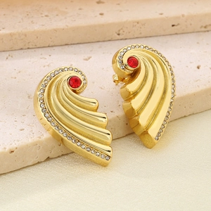 Detailed close-up of golden wing earrings featuring a red center stone and white diamonds