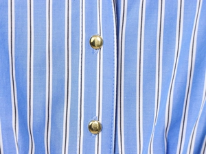 Detailed macro view of blue and white vertical striped fabric with gold metal buttons