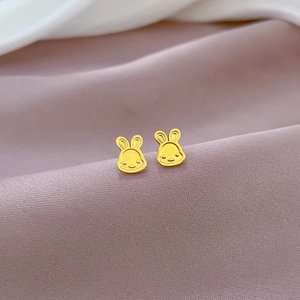 Macro view of gold bunny stud earrings on luxury purple satin fabric backdrop