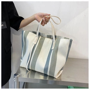 Detailed macro of green and grey striped canvas tote bag on industrial steel surface