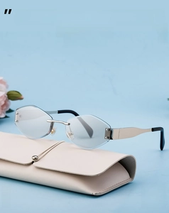Close-up of rimless diamond cut sunglasses with silver temples on a beige leather case