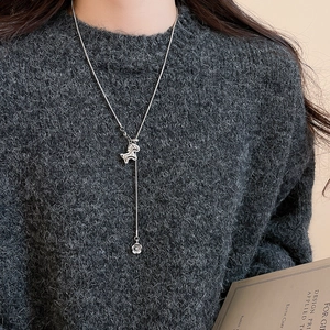 Close-up of silver zircon horse necklace worn over a dark grey sweater for styling