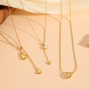 Detailed view of three 18k gold plated stainless steel heart necklaces with tassels