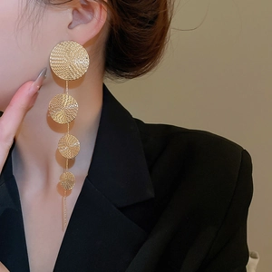 Macro detail of long gold drop earrings with textured round metal beads on model