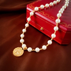 Macro view of a gold-plated coin pendant with a pearl necklace on a velvet box