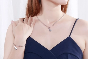 Detail of silver guitar pendant on link chain necklace and bracelet worn by model