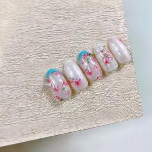 Faux ongles fleurs de cerisier roses avec pointes bleues, perles et fini nacré