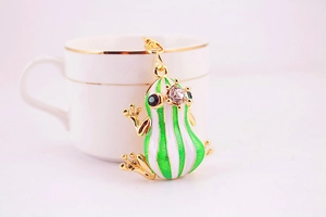 Detail of green enamel frog keychain with sparkling crystals on a polished gold-plated ring