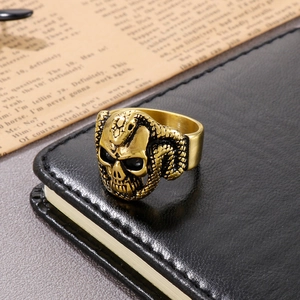 Detail of gothic skeleton snake ring in antique gold finish on black leather surface