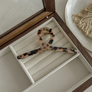 Macro shot of large leopard print acetate claw clip in a velvet lined wooden jewelry box