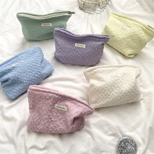 Flat lay of colorful pleated fabric cosmetic bags in pastel shades with Sozakka tag