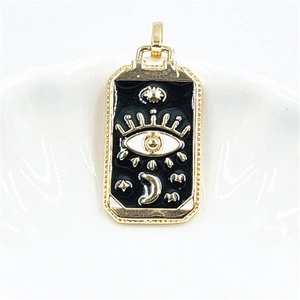 Detail of tarot pendant featuring a golden eye, crescent moon, and stars on black enamel