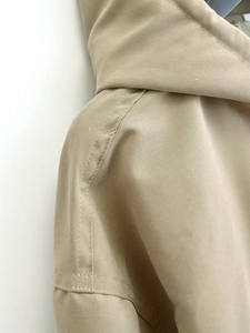 Detailed macro view of khaki drawstring jacket shoulder stitching and fabric texture