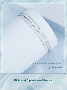 Close-up of triple-layer silver bracelet with snake and bead chains on white stand