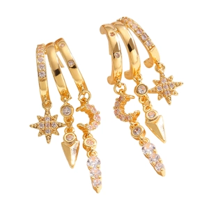 Detail of gold layered hoop earrings featuring hanging star, arrow, and moon zircon charms