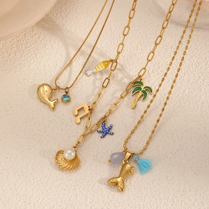 Set de colliers dorés thème océan avec pendentifs étoile de mer et coquillage sur fond beige