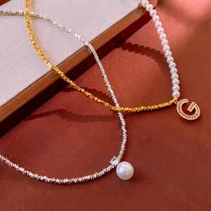 Détail d'un collier de perles de luxe avec pendentif lettre G en or et chaîne en zircon