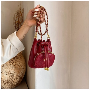 Close-up of red quilted mini drawstring bucket bag with leather-woven metal chain strap
