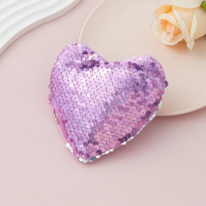 Detail of purple gradient sequin heart accessory on an elegant pink textured background