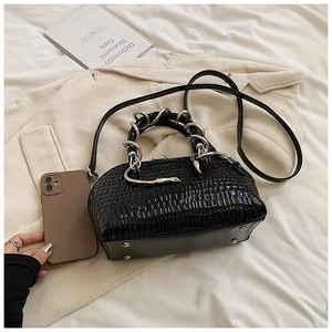 Detail of black faux crocodile leather shell bag with unique silver snake-shaped handle