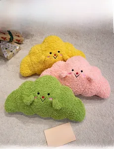 Three colorful cloud-shaped plush pillows with smile embroidery on soft grey carpet