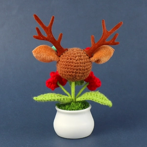 Close-up of handmade crochet reindeer head with festive red flowers in a white ceramic pot