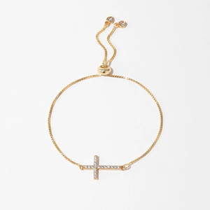 Close-up of gold bolo bracelet with zircon-encrusted cross and heart charms