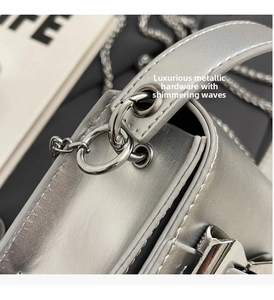 Detail of metallic silver crossbody bag showing the glossy finish and metal chain strap