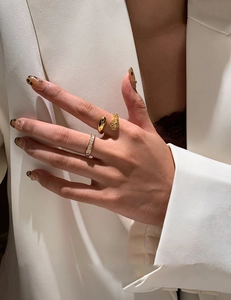Detail of stacked gold teardrop and pave rings on finger with stylish leopard nails