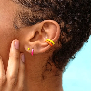 Detail of colorful enamel sterling silver hoop earrings and ear cuffs on a model