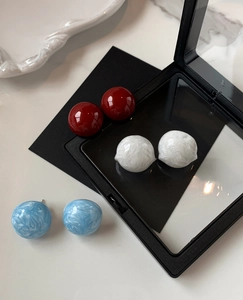 Vue détaillée de boucles d'oreilles boules en résine rouge et motifs marbrés blanc bleu