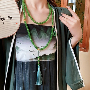 Détail du collier long de style chinois avec anneau en jade vert et pompon en soie