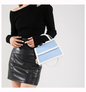Lifestyle shot of sky blue and white contrast handbag shown on a model for size