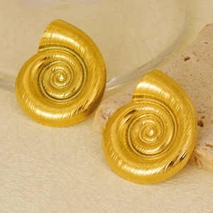 Macro shot of gold-plated spiral snail shell earrings on a natural stone background