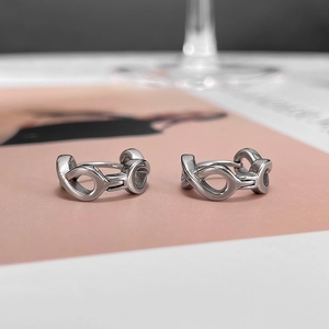 Macro detail of silver interlocking infinity earrings on a soft minimalist background