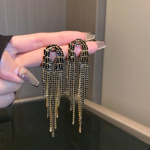 Detailed close-up of dark style tassel earrings with black beads and gold chains