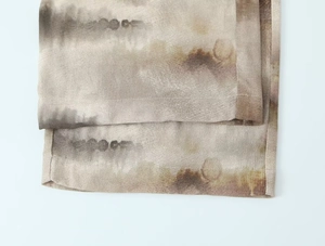 Close-up of earthy tie-dye fabric texture and fine hem stitching on casual suit
