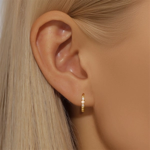 Close-up of golden S925 sterling silver hoop earring with pearls and zircons on ear