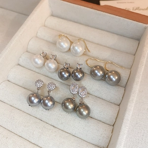 Close-up of pearl earring sets with cubic zirconia and metal accents in a jewelry box