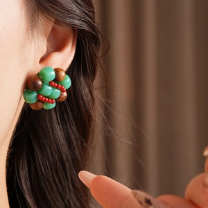 Detailed close-up of ethnic beaded stud earrings featuring green and brown resin beads