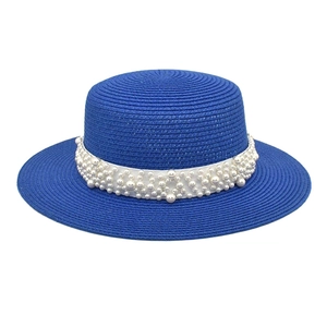 Détail d'un chapeau de paille bleu marine avec perles élégantes sur un ruban blanc satiné